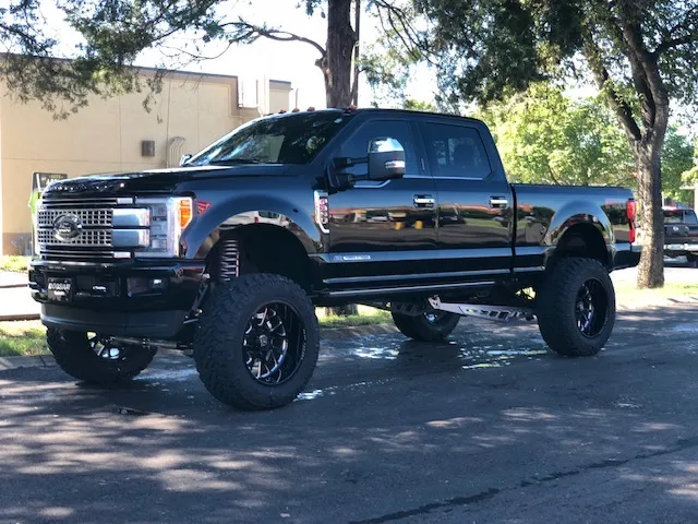 Black lifted Ford Super Duty on custom black wheels outside the shop