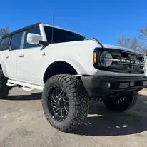 White Ford Bronco on black off-road wheels and mud tires