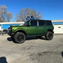 Green Ford Bronco with fresh window tint outside the Midwest Custom Trucks shop